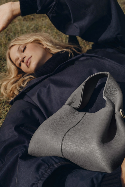 Elegant Minimalist Slate Grey Pebbled Leather Top Handle Handbag with Soft Sculptural Silhouette and Gold Hardware – Modern Quiet Luxury Designer Accessory Product Shot