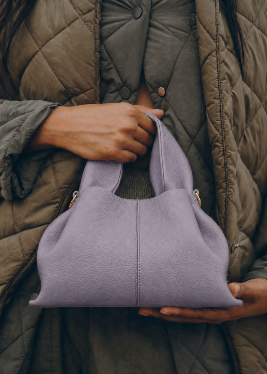 Elegant Minimalist Resort Look Featuring Flowing Ivory Tunic Dress and Draped Neutral Layers with Structured Soft Lilac Leather Top Handle Handbag – Modern Quiet Luxury Womenswear Editorial Style