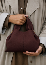 Refined Minimalist Winter Outfit Featuring Soft Ivory Textured Coat and Cream Tailored Trousers with Deep Burgundy Leather Crossbody Top Handle Handbag – Elegant Quiet Luxury Womenswear Editorial Style