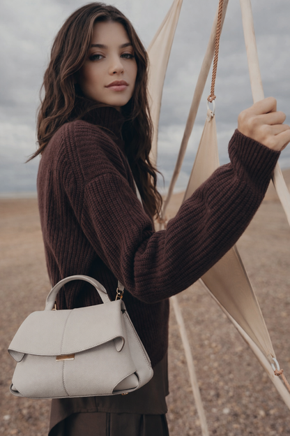 Elegant Ivory Pebbled Leather Top-Handle Shoulder Bag with Fold-Over Flap and Adjustable Strap Styled in Cozy Knitwear Portrait