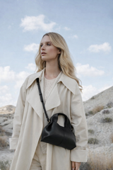 Sophisticated Minimalist Trench Coat Ensemble Featuring Oversized Stone Beige Outerwear and Layered Neutral Tailoring with Structured Black Leather Top Handle Handbag – Modern Quiet Luxury Womenswear Editorial Look