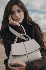 Elegant Ivory Pebbled Leather Top-Handle Shoulder Bag with Fold-Over Flap and Adjustable Strap Styled in Cozy Knitwear Portrait