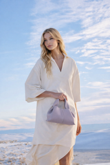 Elegant Minimalist Resort Look Featuring Flowing Ivory Tunic Dress and Draped Neutral Layers with Structured Soft Lilac Leather Top Handle Handbag – Modern Quiet Luxury Womenswear Editorial Style