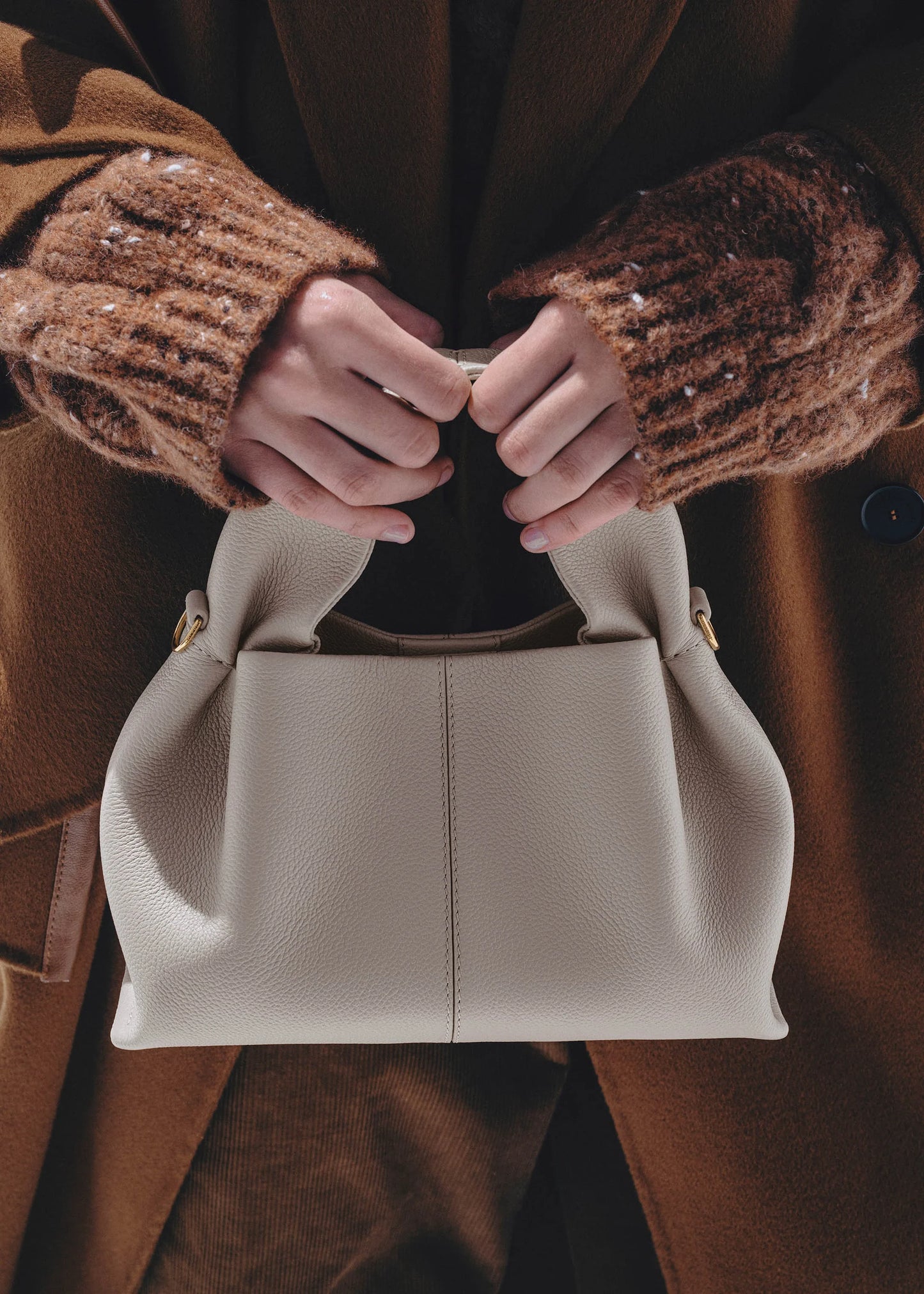 Elegant Winter Minimalist Look Featuring Rich Chocolate Wool Coat and Textured Knit Sleeves with Structured Stone Beige Leather Top Handle Handbag – Timeless Quiet Luxury Womenswear Editorial Style