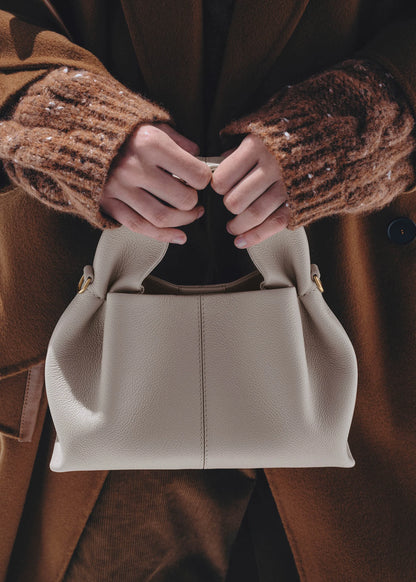 Elegant Winter Minimalist Look Featuring Rich Chocolate Wool Coat and Textured Knit Sleeves with Structured Stone Beige Leather Top Handle Handbag – Timeless Quiet Luxury Womenswear Editorial Style
