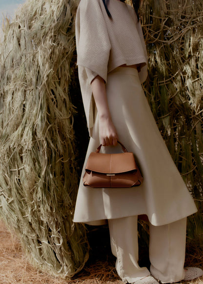 Elegant Tan Pebbled Leather Top-Handle Mini Handbag with Fold-Over Flap and Gold-Tone Hardware Styled with Neutral Knit Ensemble