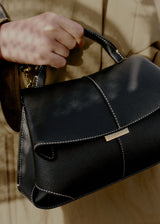 Elegant Black Pebbled Leather Top-Handle Handbag with Fold-Over Flap, Contrast Stitching, and Gold-Tone Hardware