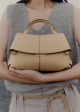 Elegant Beige Pebbled Leather Top-Handle Handbag with Fold-Over Flap and Minimalist Structured Silhouette Styled in Soft Neutral Look
