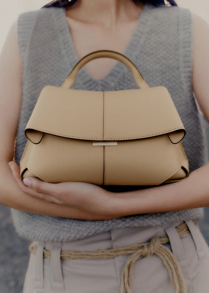 Elegant Beige Pebbled Leather Top-Handle Handbag with Fold-Over Flap and Minimalist Structured Silhouette Styled in Soft Neutral Look