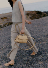 Elegant Beige Pebbled Leather Top-Handle Handbag with Fold-Over Flap and Minimalist Structured Silhouette Styled in Soft Neutral Look
