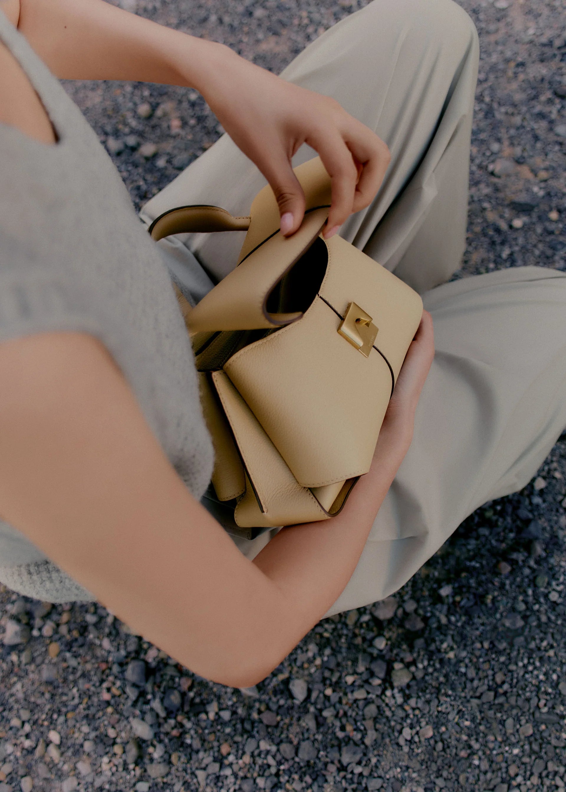 Elegant Beige Pebbled Leather Top-Handle Handbag with Fold-Over Flap and Minimalist Structured Silhouette Styled in Soft Neutral Look