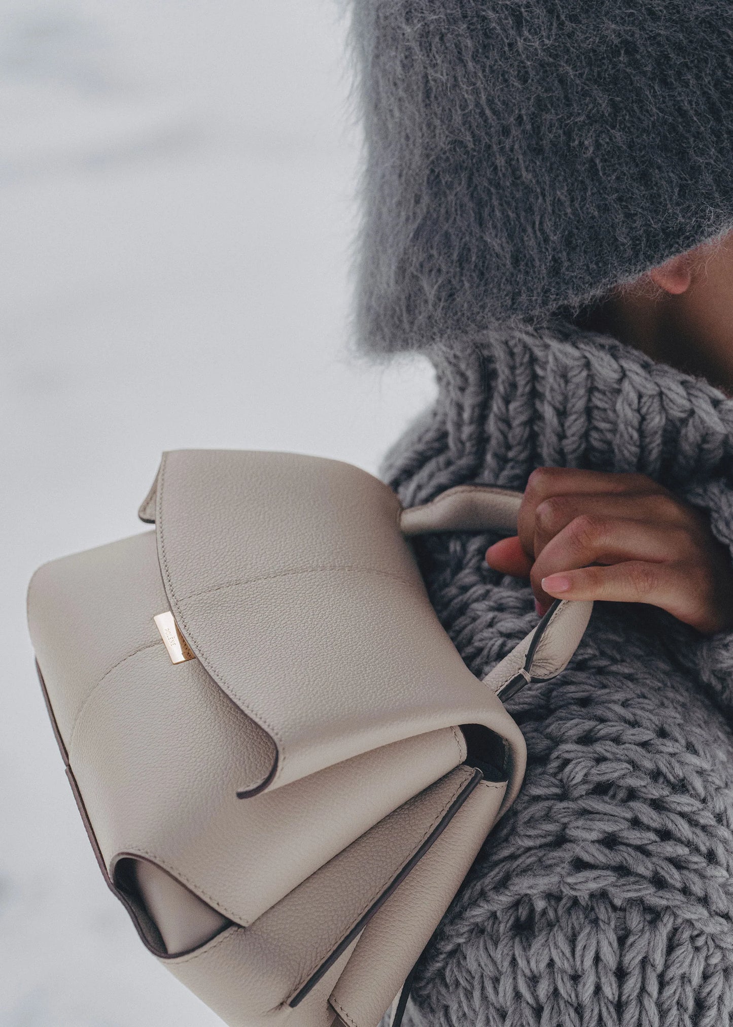 Elegant Taupe Pebbled Leather Top-Handle Crossbody Bag with Fold-Over Flap and Adjustable Strap Styled with Oversized Chunky Knit Sweater