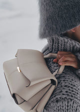 Elegant Taupe Pebbled Leather Top-Handle Crossbody Bag with Fold-Over Flap and Adjustable Strap Styled with Oversized Chunky Knit Sweater