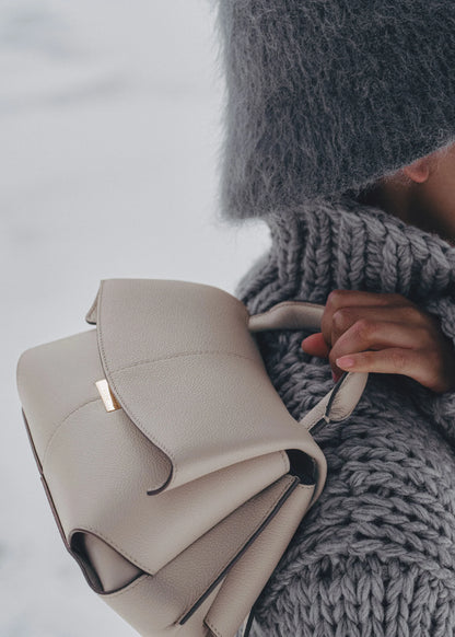 Elegant Taupe Pebbled Leather Top-Handle Crossbody Bag with Fold-Over Flap and Adjustable Strap Styled with Oversized Chunky Knit Sweater