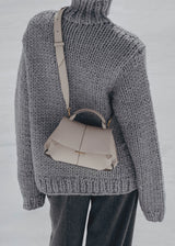 Elegant Taupe Pebbled Leather Top-Handle Crossbody Bag with Fold-Over Flap and Adjustable Strap Styled with Oversized Chunky Knit Sweater