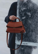 Elegant Cognac Pebbled Leather Top-Handle Shoulder Bag with Fold-Over Flap, Adjustable Strap, and Gold-Tone Hardware Styled in Modern Winter Look