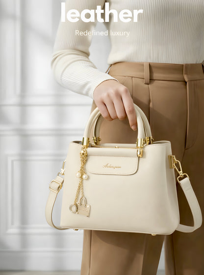 Smooth minimalist front panel enhanced with a structured flap detail and a detachable gold charm chain featuring pearl and mini handbag accents for a refined luxury-inspired finish.