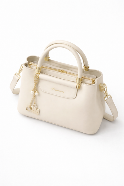 Smooth minimalist front panel enhanced with a structured flap detail and a detachable gold charm chain featuring pearl and mini handbag accents for a refined luxury-inspired finish.